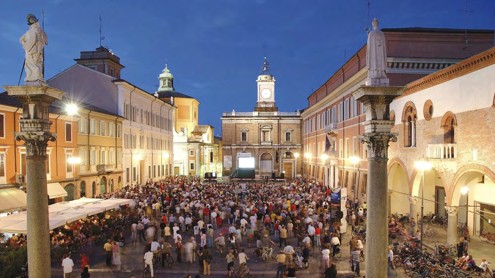 Crowds filling Ravenna's city-centre square at dusk in front of a big screen